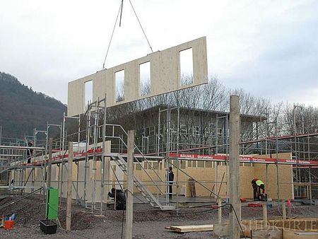 Ein Wandmodul wird auf das Fundament gesetzt.